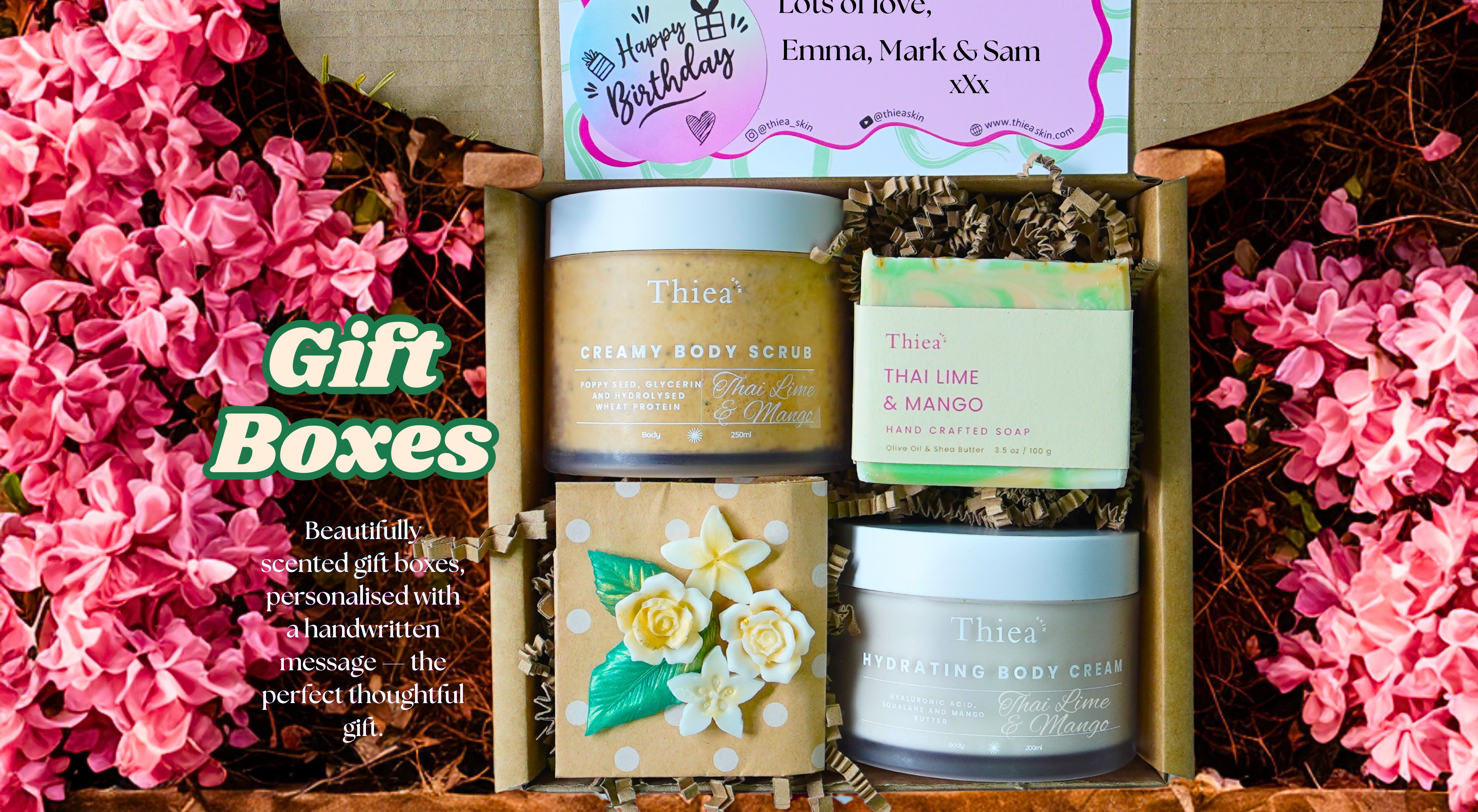 Gift box with skincare products and a personalized card, surrounded by pink flowers.