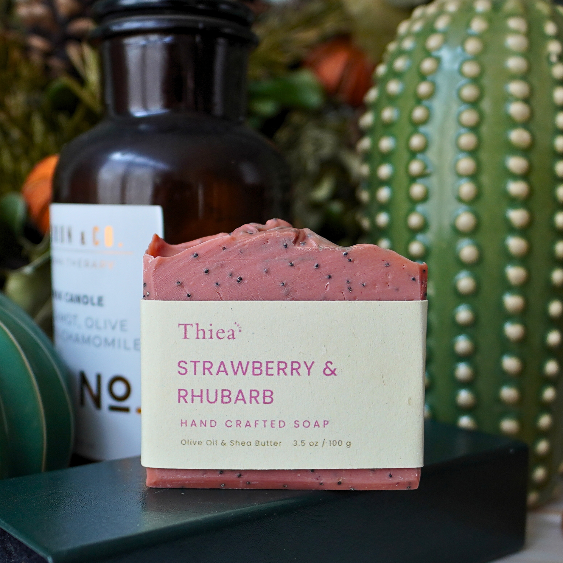 Thica Strawberry & Rhubarb soap bar with a bottle and cactus in the background