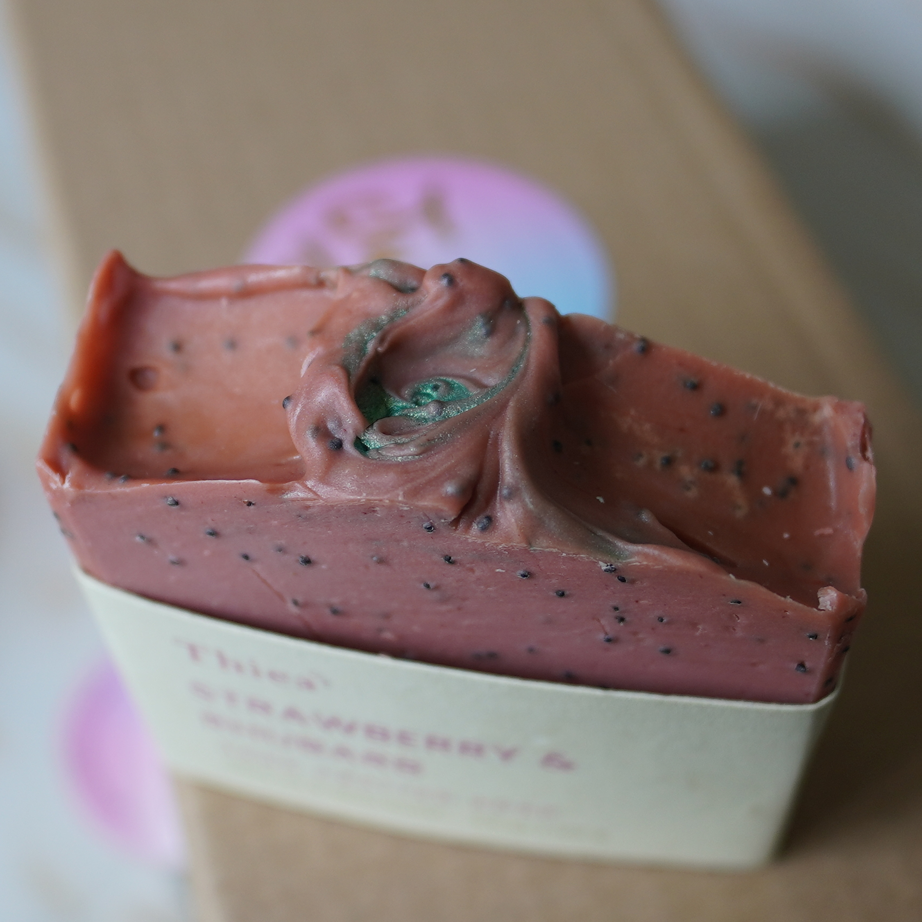Pink and green swirled soap bar in a box with a blurred background