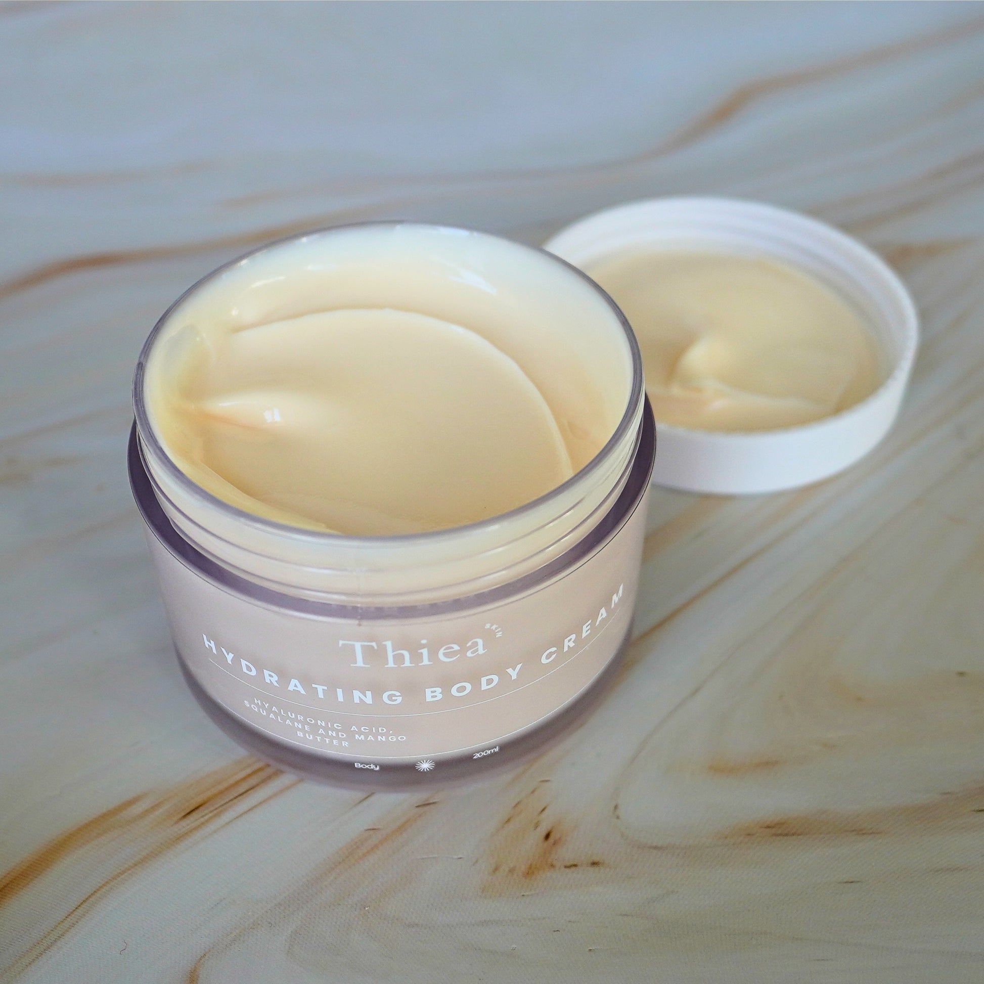 Thiea hydrating body cream jar on a wooden surface